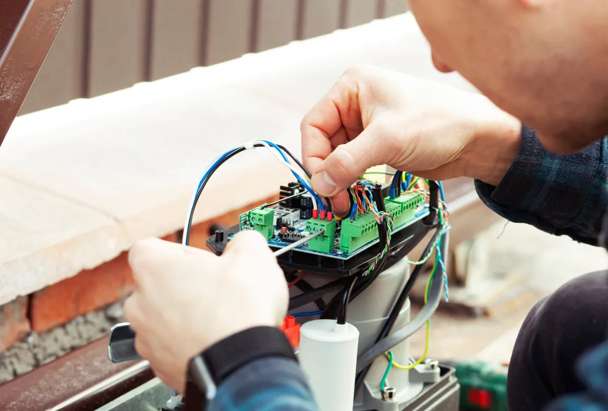 Technicien réparant le moteur d’un portail électrique défectueux.